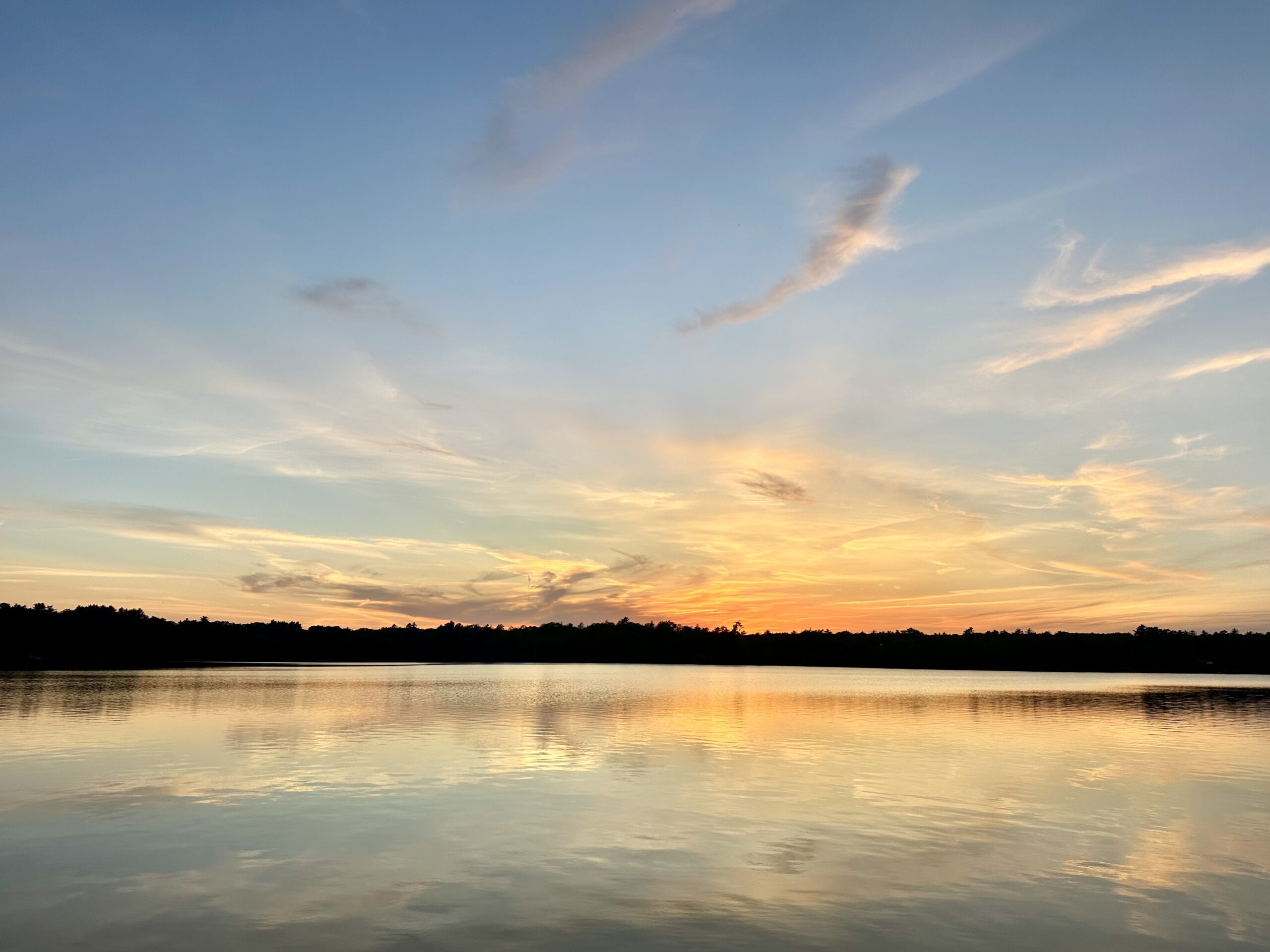 Sunset reflecting on calm water with a colorful sky.